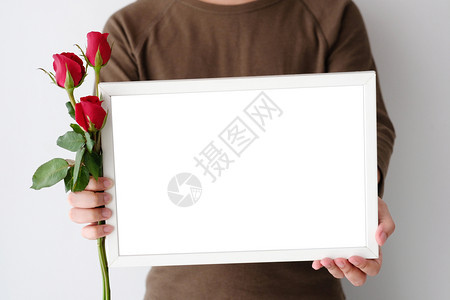 木头男子手拿着红玫瑰和白木框站在背景上立周年纪念日泰国图片