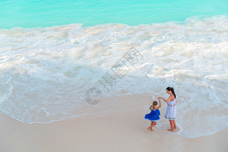年轻的母亲和她小女儿在海滩上美丽的母亲和女儿在海滩上白种人岸绿松石图片