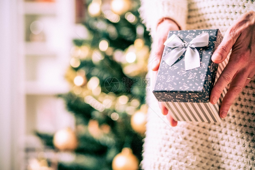 盒子假期女在节日灯前手握圣诞礼物盒的手图片