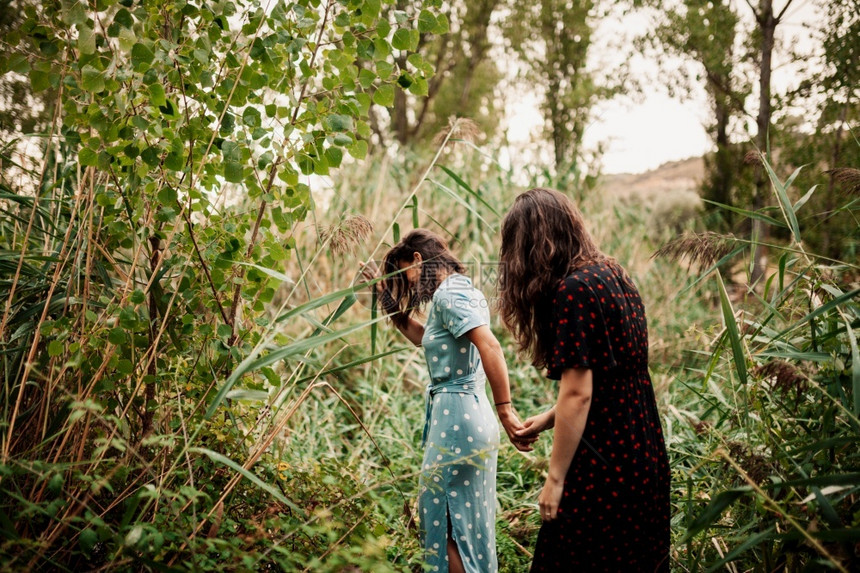 两名身穿服装和运动鞋的女青年在田野中走过夏天自然腰部图片
