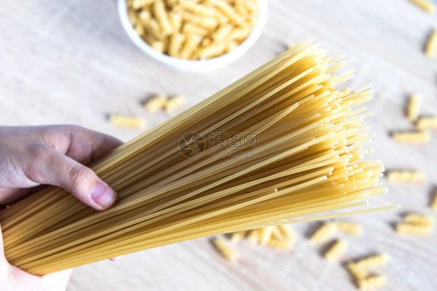 桌子散落意大利面背景下的手干意大利面健康饮食或生活方式散落意大利面背景下的手中干意大利面午餐厨房图片