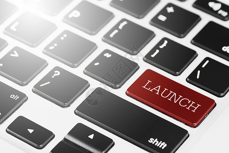 白色的网站LAUNCH用于商业和技术概念的膝上型计算机的红色按钮键盘开球背景图片