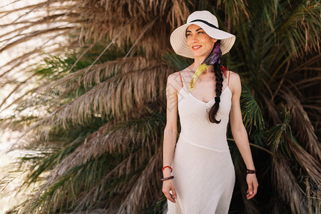 围巾放松美丽身着白裙子靠近棕榈树的年轻女子图片