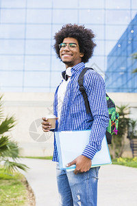 拿着咖啡书籍背着包的男性站在校园户外图片