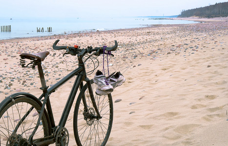 运动鞋挂在自行车上在沙滩图片