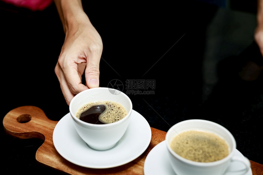 厨房木制的两杯咖啡放在木板上手咖啡师坐在店的角对着镜头拿铁图片