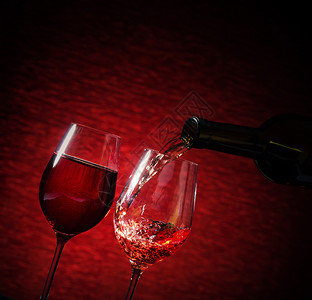 填充红色的酒倒在杯子上明红的色背景上酒倒在杯子气泡图片