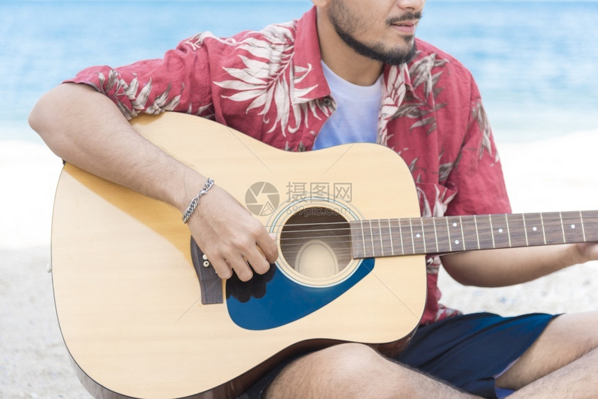 女孩英俊的音乐家在海滩上弹吉他放松生活方式旅游概念电的玩图片