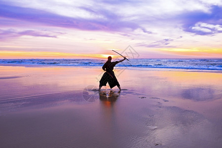 狂怒在海滩日落时带本的年轻武士女子Katana图片