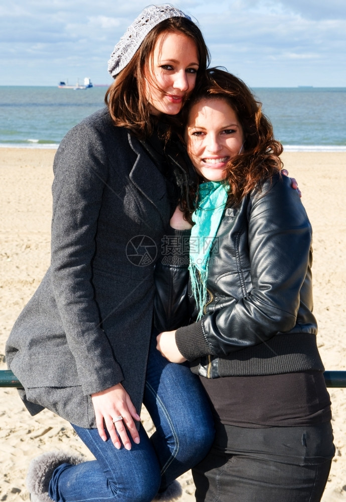 海滩上的两个年轻女子在美丽的秋天站在海面前摆着姿势一种眼睛女图片