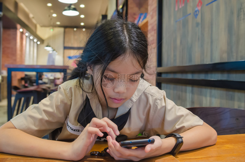 在餐厅里使用手机的小女孩图片