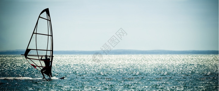全景唤醒行动风帆冲浪者剪影映衬着波光粼的蓝色大海图片