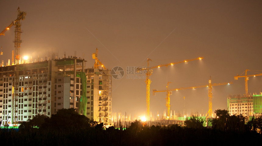 工业建造起重机和夜间建筑的设水泥摩天大楼屋图片