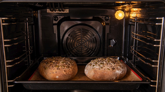 热的工作小麦手面包在烤箱中烘图片