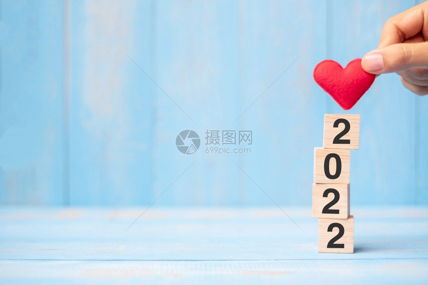 十二月商人手握红色心形在蓝桌子背景上超过20个木制立方体并为文本业务分辨率新年你和情人节快乐日概念提供复制空间二月日历图片