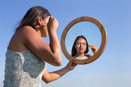 妇女用化妆品在镜子里外面有蓝天空黑色的脸舍内维尔图片