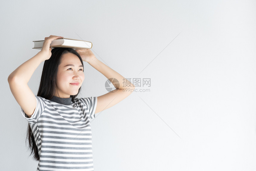 站在白色背景前拿着一本书放在头顶的女性图片
