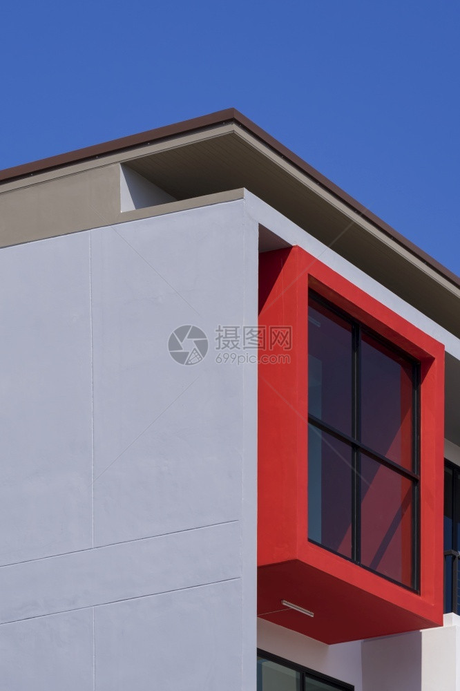 阳光现代办公建筑墙上红色阳台玻璃墙的低角度和侧面视图垂直框蓝色天空背景下的蓝色天空背景正面窗户图片