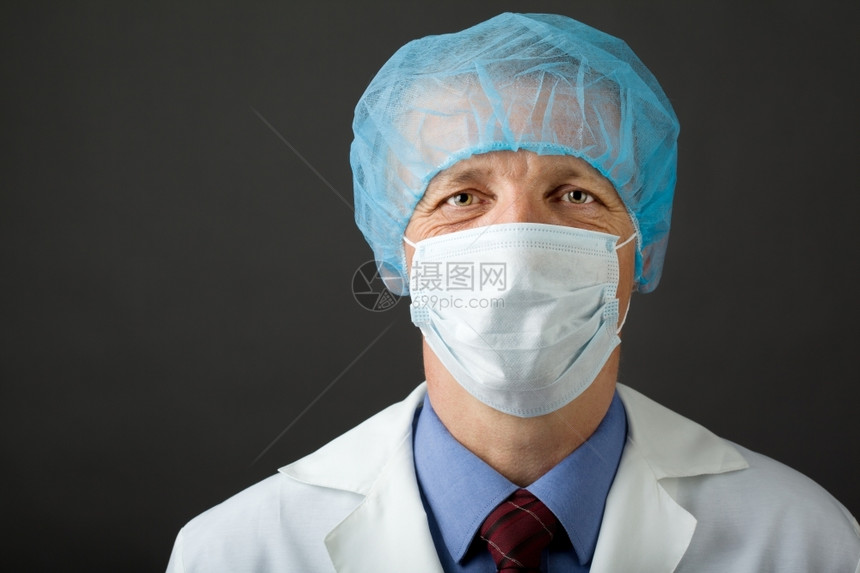 白色的职业戴面罩和帽子看镜头的男医生灰色图片