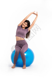 坐在瑜伽球上拉伸的年轻女子图片