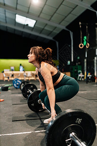力量强大的女举重器准备在健身房升起年轻的专注图片