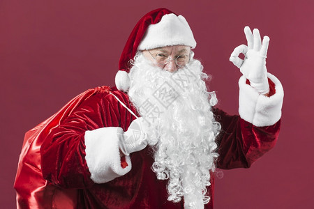 带麻袋的圣诞老人表现出好的姿态保持微笑打手势图片