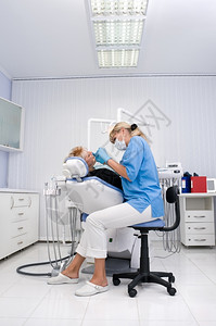 白色的医生与牙办公室的病人一起工作以及口腔科内部的图片
