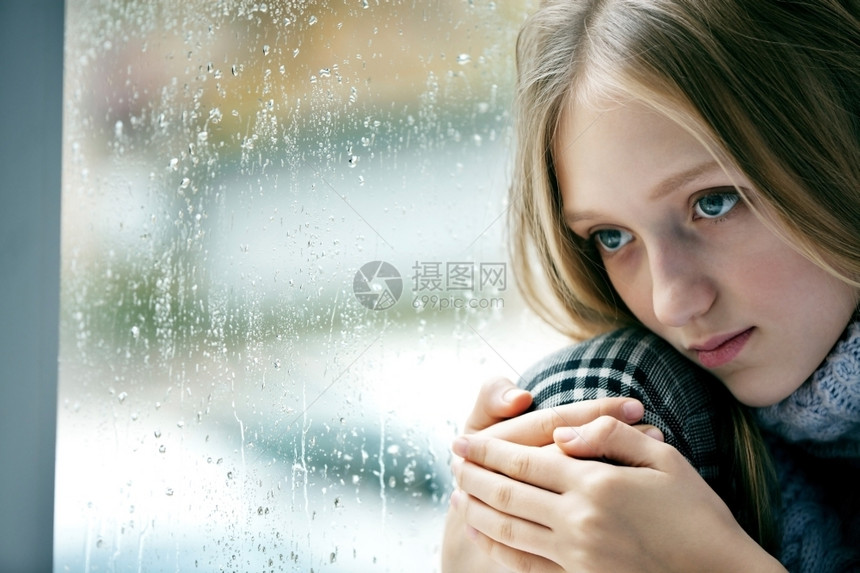 沮丧秋天女孩们一个长金发头的悲伤女孩情感肖像她坐在雨秋日的窗口上图片