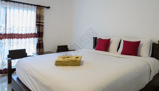 床单织物白色卧室有整洁的国王床和黄色折毛巾公寓图片