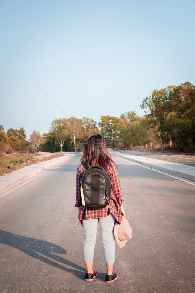 白色的带背在沥青路农村地区行走的女旅妇自然徒步旅行图片