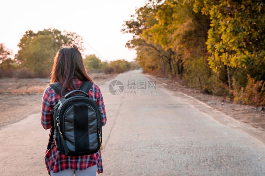 微笑带背在沥青路农村地区行走的女旅妇背包客吸引人的图片