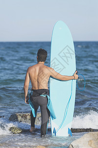 冲浪者在海滩上拿着冲浪板背影图片