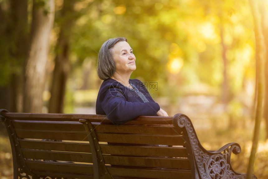 年长妇女坐在秋天公园的长椅上年妇女坐在秋日公园的长凳上树叶一种外部图片