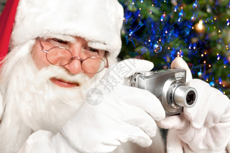 克劳斯圣诞老人在背景中拍摄一个数码相机圣诞树垂直的节假日图片