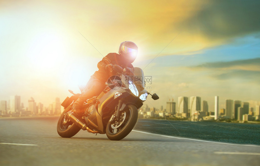 年轻男子骑着大摩托车直的弯曲与城市建筑背景相靠旅行人们自车图片