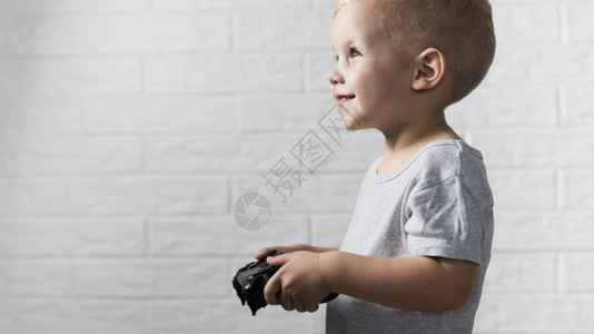 侧边视图小男孩玩控制器操纵杆快乐的年轻图片