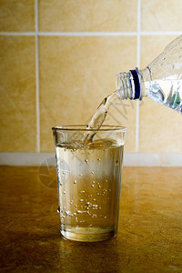 饮料瓜拉纳皮瓶子从塑料中将新鲜矿泉水倒入厨房的一个简单玻璃杯里图片