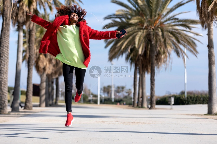 非洲裔年轻黑人女孩在城市背景中跳起的ffro发型随意的城市图片