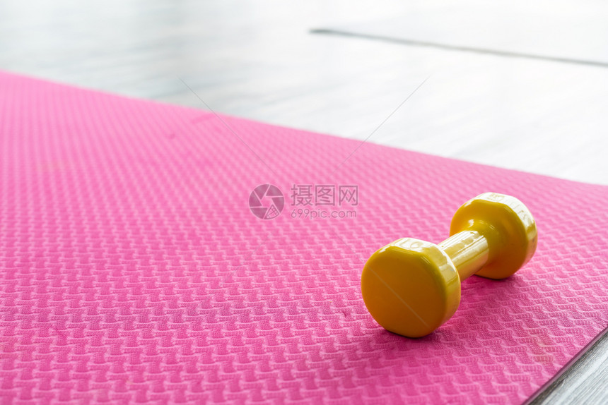木地板背景的空粉红色橡胶地板上的黄色哑铃带有空间健康和运动概念的平面图象房间地起重图片