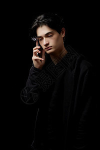 一种穿着黑帽衫的人青年在色背景和手机握着电话伪装图片