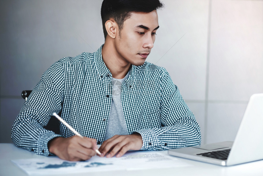 幸福积极的专业在办公室用电脑笔记本上工作的青年商人在办公桌旁工作临时服人图片