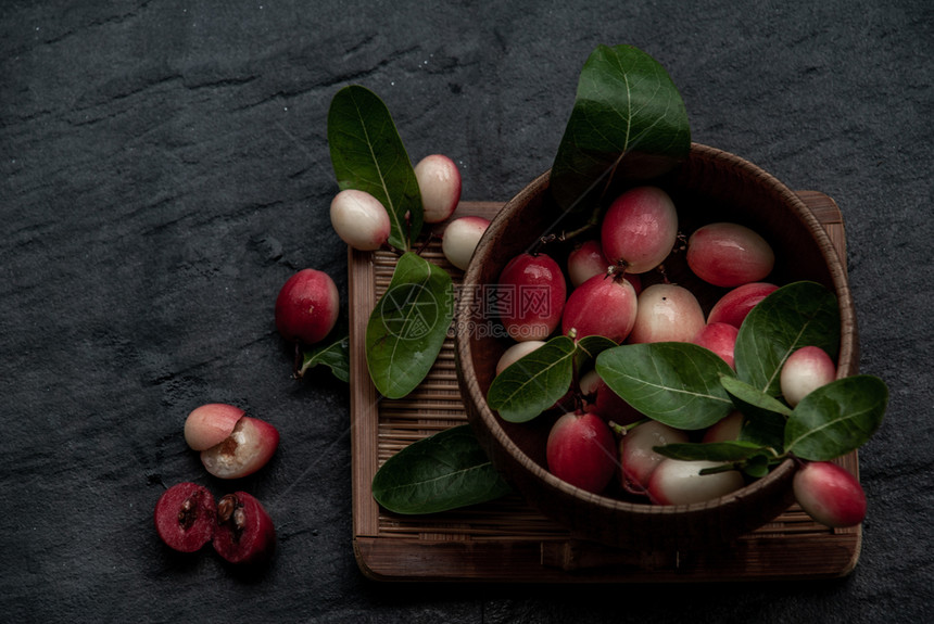 新鲜的生卡隆达孟加拉醋栗Carandas李子或Karonda水果CarissacarandasL酸味水果在柳条木杯中从顶部斜视图图片