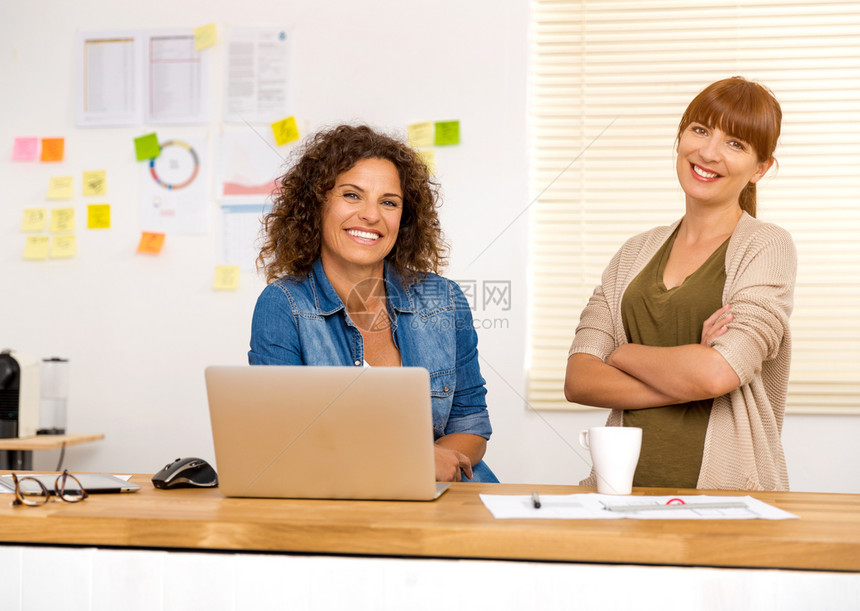 放松随意的两个快乐女商人在一个办公室起工作桌子图片