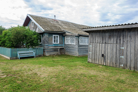 衬套在俄罗斯村的旧木屋和草棚夏季日建造粗糙的背景图片