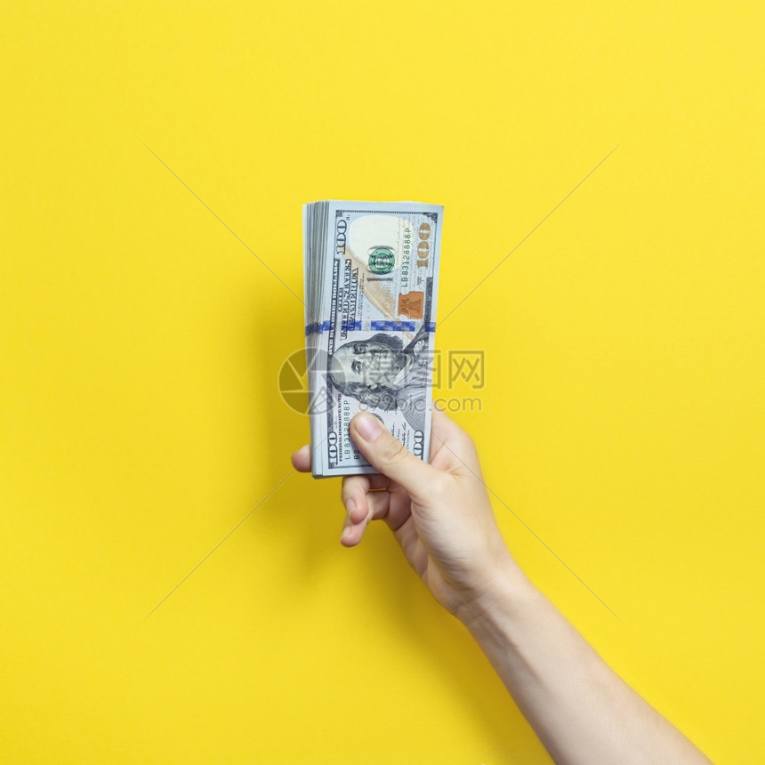 手握着一大堆钞票孤立在黄色背景的财富或贷款概念上黄色的收益纸币图片