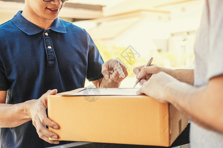 用户在剪贴板上签名以便从在家的专业送货员那里接收包裹运输签约货物图片