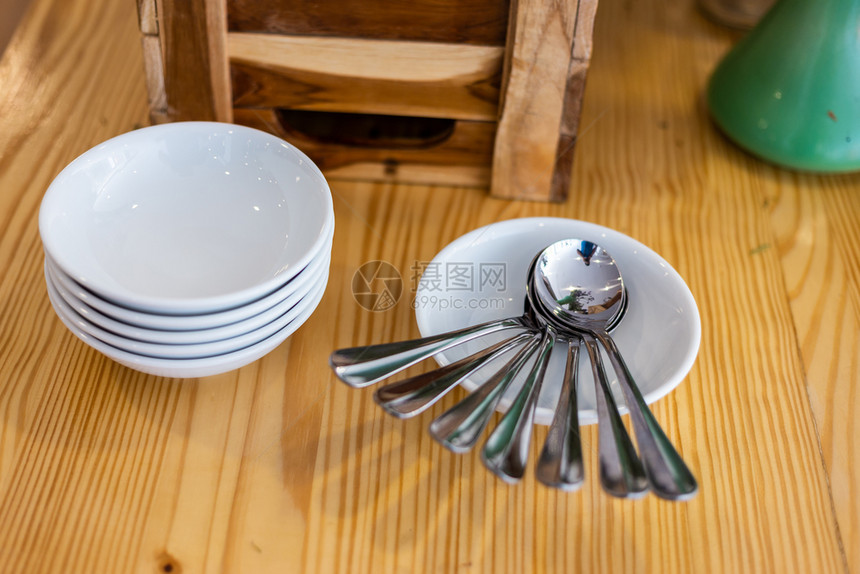 许多勺子和盘放在旅馆餐桌装饰板上的饭碗一顿餐厅银器图片
