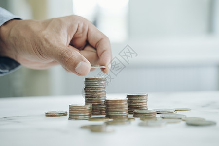 经济型货币兴趣商人节约钱的概念手拿硬币装在玻璃瓶里图片