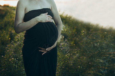 怀孕妇女拥抱肚子站在户外被大自然包围着的外表怀孕期待母概念亲孩子接触图片