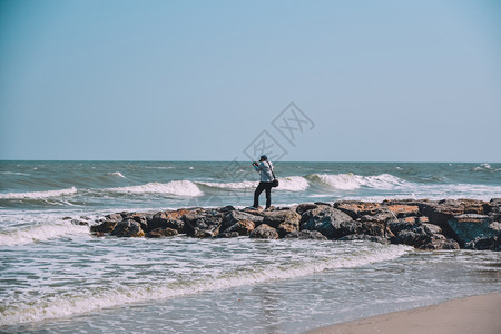 海滩岩石上的男人图片